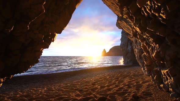 View From the Stone Cave on the Sunset Sea and the Beach the Volcanic Rock of the Cave is Lit By the alt