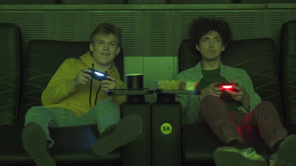 Young Gamers in a Movie Theater Two Friends Playing Video Games on a Game Console Guys Give Five and alt