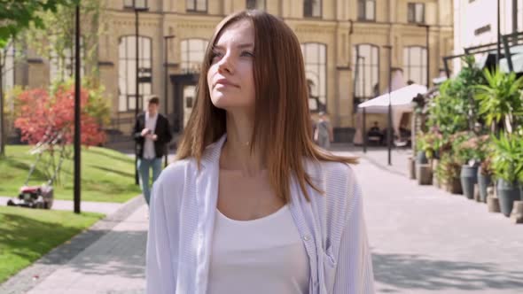 Relaxed young woman walking ath the city street.