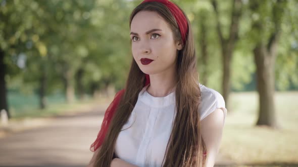 Portrait of Gorgeous Young Caucasian Woman Waiting for Boyfriend in Sunny Summer Park, Dissatisfied alt
