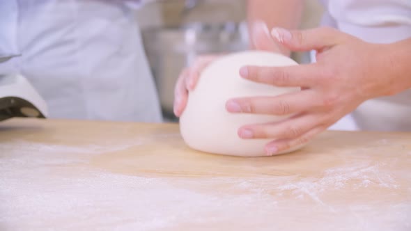 Closeup of Dough Kneaded By Baker on a Wooden Board Sprinkled with Flour alt