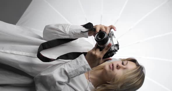 Portrait of a Beautiful Young Woman Photographer in a White Shirt with Long Blond Hair Making Shots alt