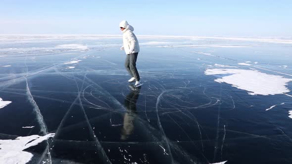 Young Adult Woman Skates on The Transparent Ice of Lake Baikal