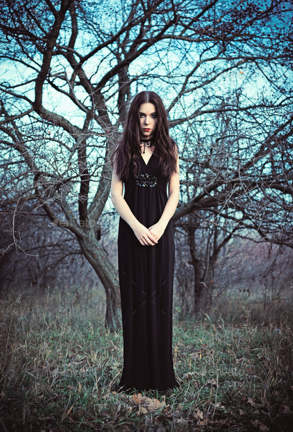 Portrait of beautiful goth girl amongst the faded trees