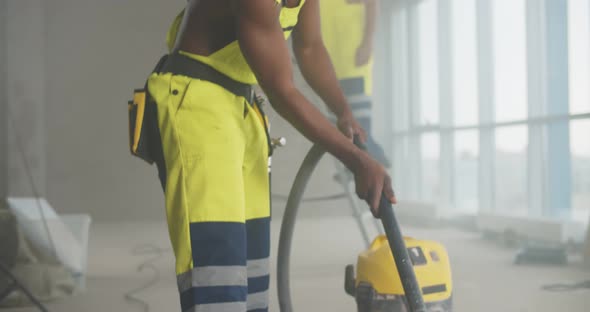 Shirtless African Builder Cleaning with Construction Vacuum Cleaner alt