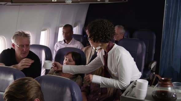 Flight attendant serving drinks to airliner passengers