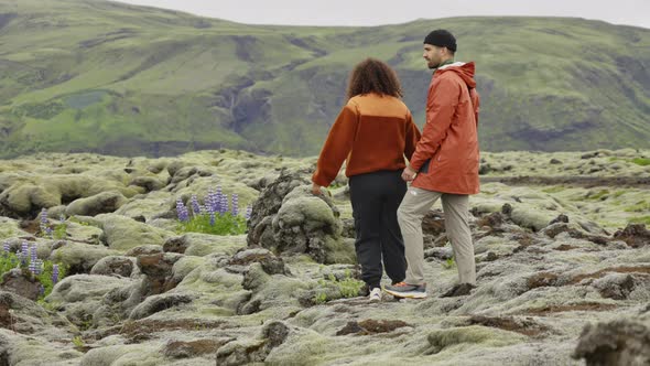 Couple Hiking over Rocks in Moss Covered Landscape alt