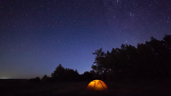 Orange Iluminated Tent in the Forest Under the Starry Sky. Timelapse alt