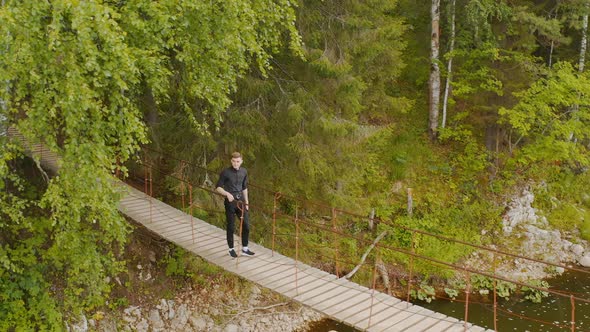 Man is walking on suspension bridge Tourist is walking along a wooden suspension bridge alt