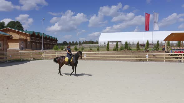 Young Caucasian Woman Rides on Horseback in Open Arena for Horses on the Hot Summer Day in the alt