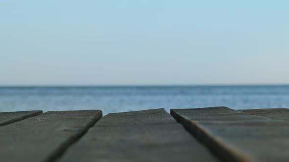 An Old Wooden Pier in Closeup Against the Background of a Blurred Blue Sea and Sky