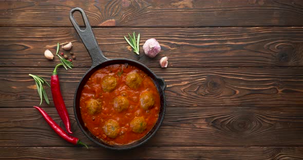 Cooking meatballs with tomato sauce in black pan