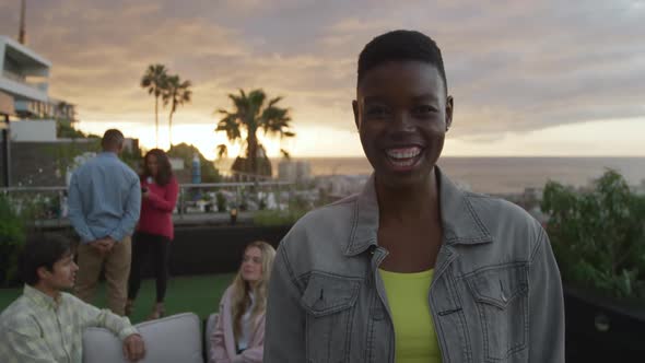 Young African American woman smiling at camera on a rooftop alt