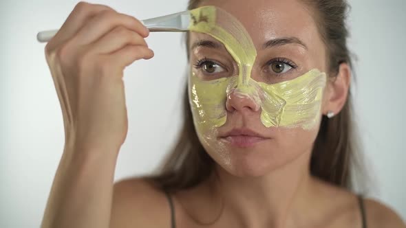 A Young Beautiful Girl Applies a Moisturizing Mask to Her Face with a Brush alt