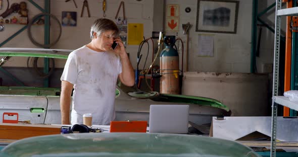 Male mechanic talking on mobile phone 4k alt