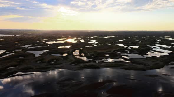 Aerial panorama of scattered lakes reflecting a golden sunrise, Potholes, Washington alt