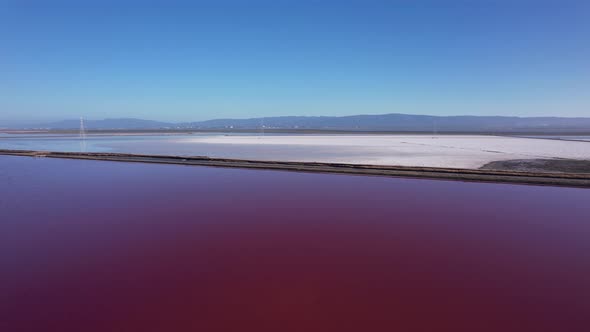 Flying diagonal over maroon colored salt ponds in East bay area, Northern California alt