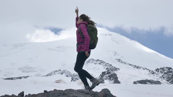 Happy Lady Sings and Dances Waving Hands Against Mountain alt