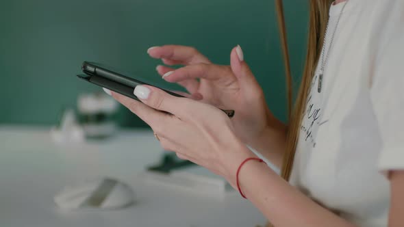 Closeup of Young Woman's Hands Holding the Phone and Tapping on the Screen