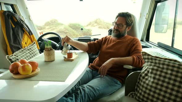 Adult man use laptop computer to work inside camper van with roaming phone connection alt