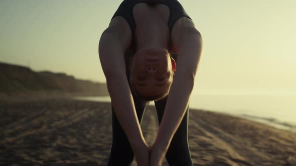 Sexy Girl Practicing Yoga on Sandy Beach Against Hills and Blue Sky Outside alt