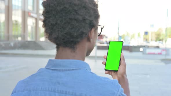 Young African Man Using Smartphone with Green Screen Outdoor alt
