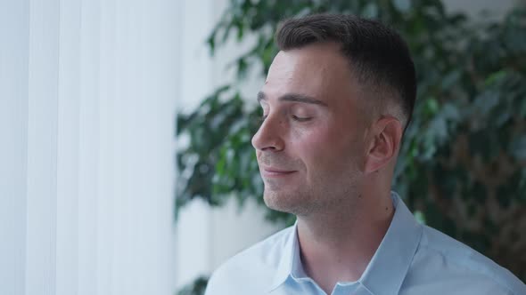 Intelligent Young Businessman Looking Out the Window Turning Looking at Camera Smiling alt