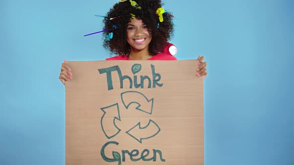 Woman holding cardboard placard with inscription think green.