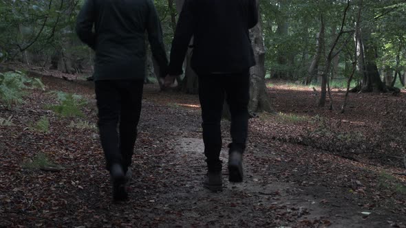Ethnic Minority Gay Couple Walking Together Holding Hands In Woodland Forest. Static Shot alt