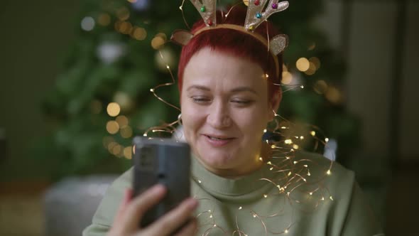 Woman reads, writes Merry Christmas and Happy New Year greetings on smartphone
