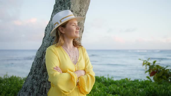 Cheerful Woman Stands By Palm Tree at Beach Hotel Resort Blue Ocean Background alt