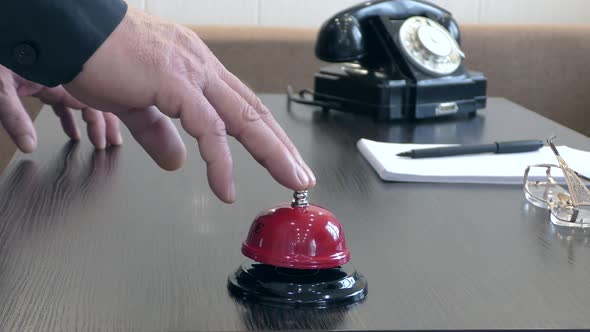 A man's hand rings a bell at the front desk. Vintage.