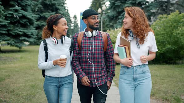 Slow Motion of Men and Women Walking Outdoors on Campus with Books and Coffee alt