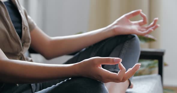 Woman Wearing Casual Jeans Clothes Sitting on Sofa in Room in Lotus Position with Crossed Legs alt