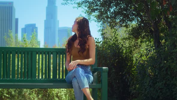 Lady Enjoy Skyscrapers View Sitting with Phone on Bench alt
