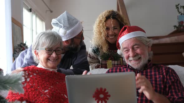 Happy family with Santa hats making video call on laptop on Christmas