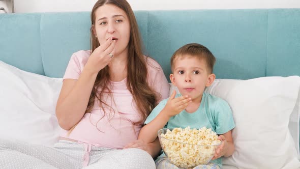 Portrait of Family in Pajamas Lying Bed with Big of Popcorn and Watching Movie on Weekend Morning alt