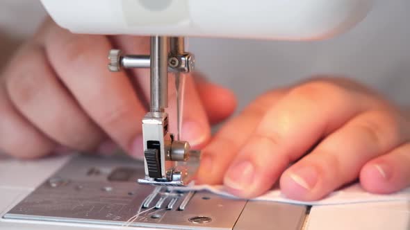 A Woman is Sewing the Hem of Curtains the Edge of a Pillowcase Clothes Sheets on Sewing Machine