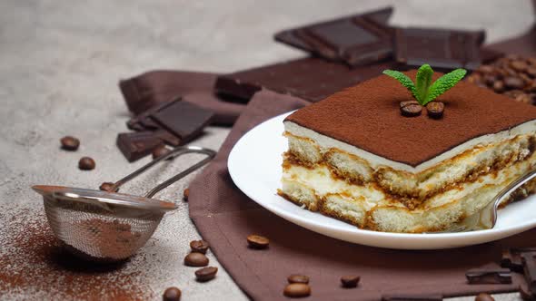 Portion of Traditional Italian Tiramisu dessert and coffee beans on grey concrete background alt