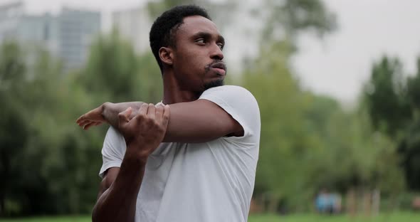African American Man Warm Up and Strech in the Park Outdoors for a Workout alt