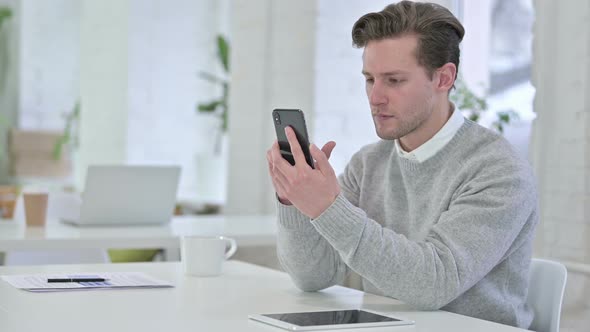 Creative Young Man Celebrating Success on Smartphone  alt