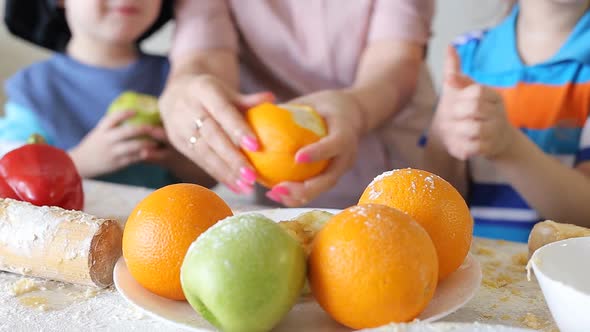 Small Children Brush Fruits with Their Mother in the Kitchen. Children's Handles Close-up