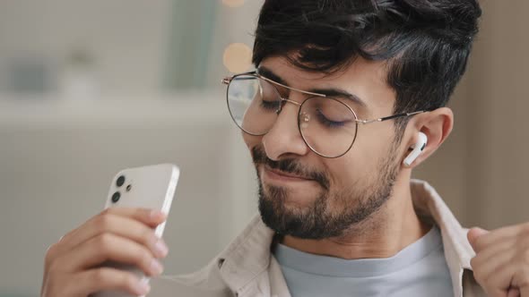 Closeup Arabic Spaniard Man Bearded Guy in Glasses Wears Wireless Modern Headphones Listening to alt
