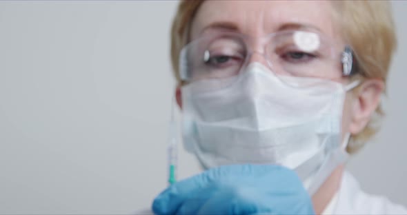 Doctor in Front of the Camera Preparing Syringe with Avaccine for Injection alt