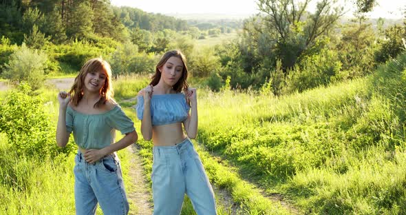 Two Carefree Girls in Stylish Summer Looks Dancing Staging Synchronously alt