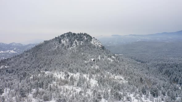 Aerial drone view of snowy wooded mountain with cabins in Colorado surrounded by snow and ice covere alt