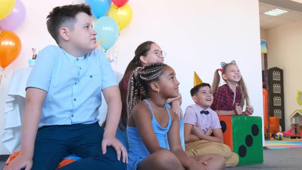 African-American Girl with Friends Enjoys Show at Birthday alt
