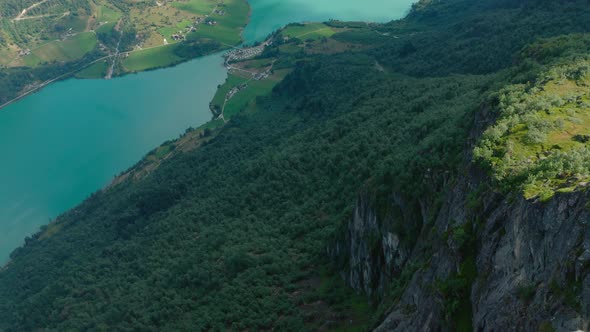Lush Forest Trees Downhill Of Klovane Summit Near Olden Village In Norway. - Aerial Pullback Shot alt