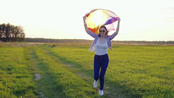 Young Woman Holding an LGBT Flag Runs Across a Field at Sunset Slow Mo alt