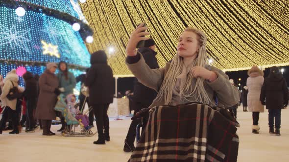 Young Woman in a Wheelchair at Christmas Celebrating on the Streets Taking a Photo and Fixes Her alt